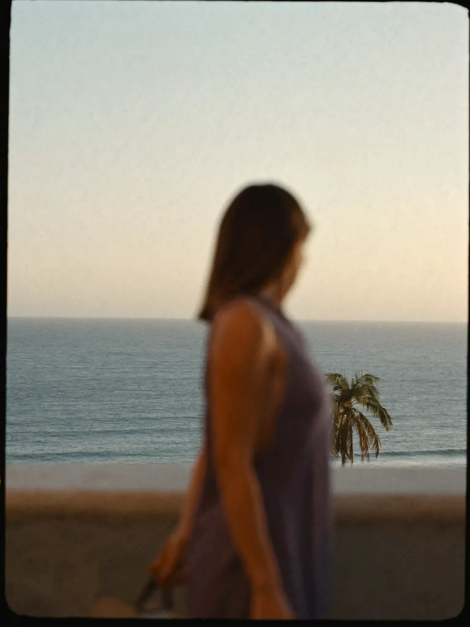 A figure on a terrace with the ocean view in focus behind (placeholder)